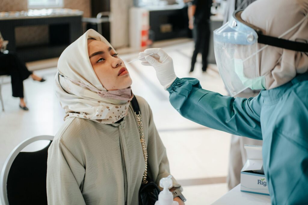 Healthcare professional conducts a swab test on a woman in a hospital setting.