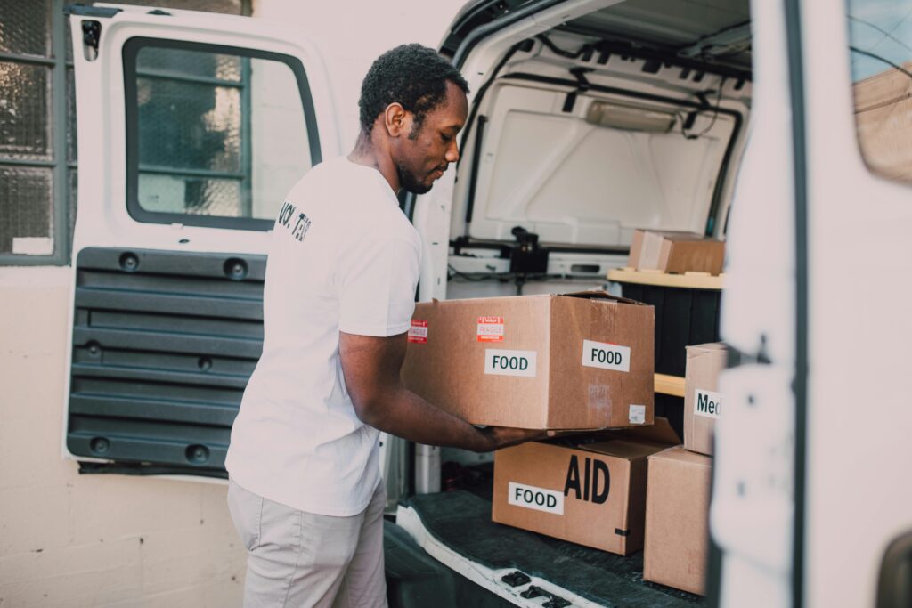 Volunteer worker loading food and aid supplies into a van for community distribution.